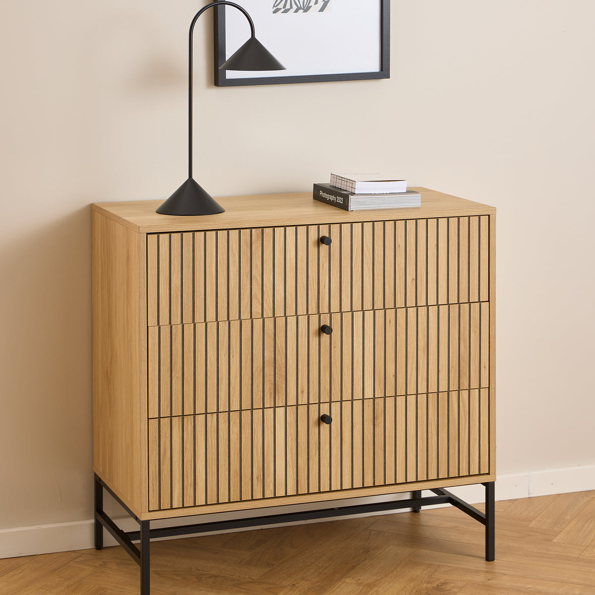 Komoda Bambouz 81x81 pod grafiką na ścianie z czarną lampą i książkami – lamelowa komoda do salonu