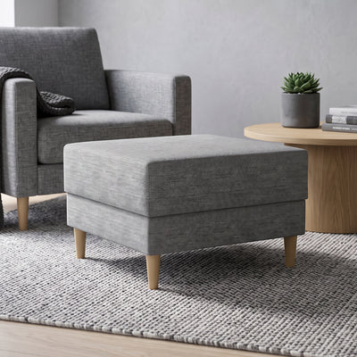 Pouf Harmi 66x66 im Wohnzimmer vor einem grauen Sessel, neben einem runden Tisch mit Sukkulente – Pouf fürs Wohnzimmer