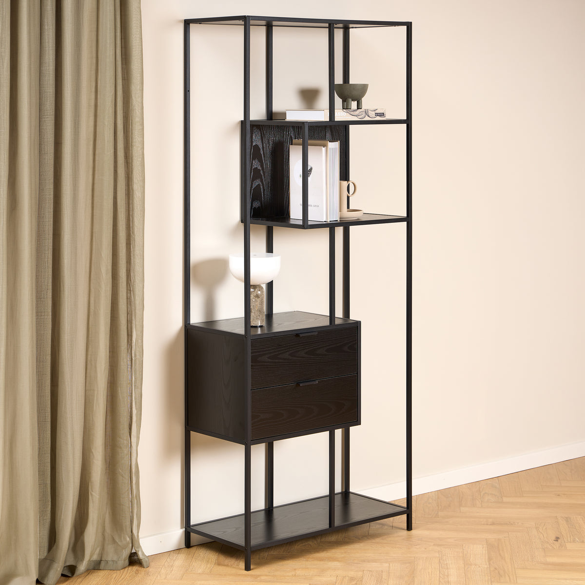 Regal „Skeleto“ 77 x 185, schwarzes Melamin, vor einer hellen Wand und einem Leinenvorhang, mit einer Lampe und Büchern