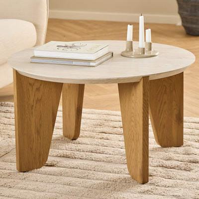 Der Couchtisch „Tendra“ (Ø 80 × 45) auf einem beigen Teppich neben einem hellen Sessel, mit Büchern und einem Kerzenständer – ein Tisch für das Wohnzimmer