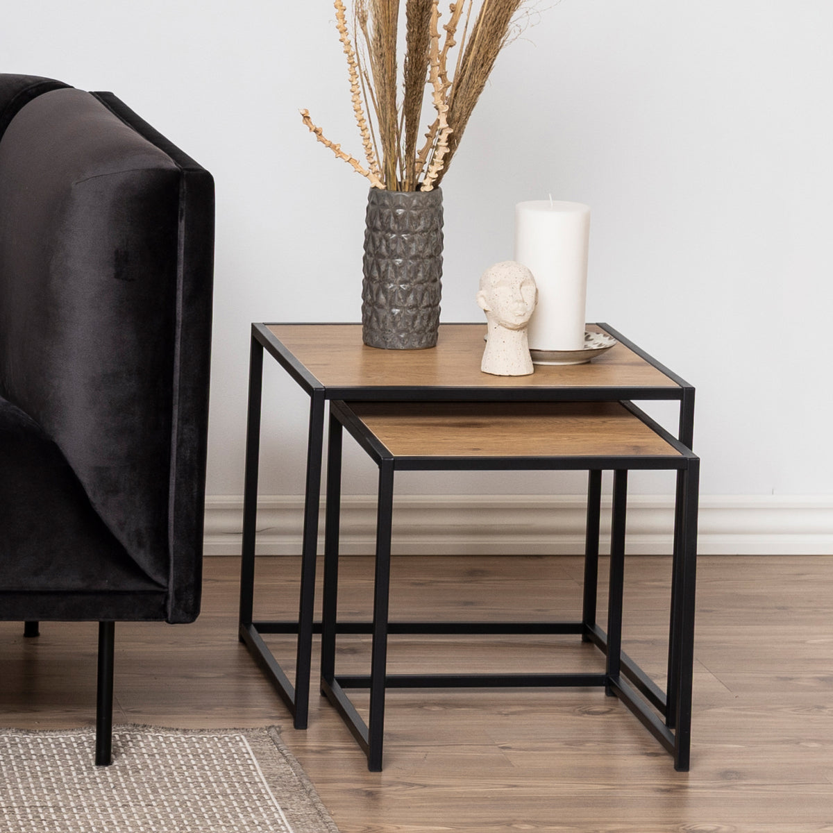 Skeleto-Couchtische 50x45 in „Wilde Eiche“ neben einem dunklen Velours-Sofa, mit einer Vase und einer Kerze – Couchtische für das Wohnzimmer