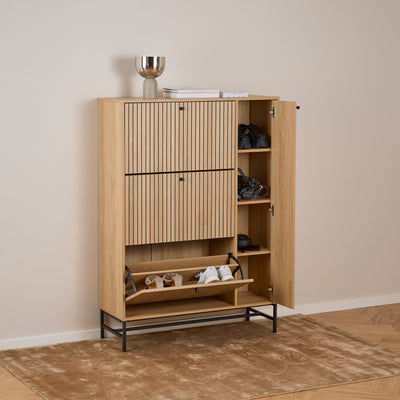 Der Schuhschrank „Bambouz 99x141“ in einem hellen Flur auf einem Teppich – offene Türen, Einlegeböden mit Schuhen und ein leicht geöffneter Stauraum
