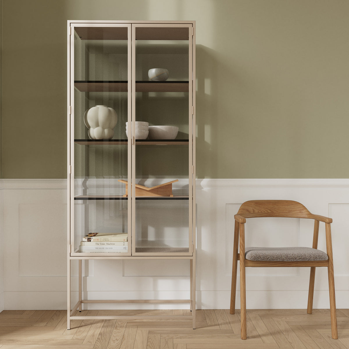 Vitrine „Skeleto“ 77 x 186, graues Melamin, vor einer olivfarbenen Wand neben einem Holzstuhl – eine Vitrine für Keramik und Bücher