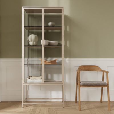 Vitrine „Skeleto“ 77 x 186, graues Melamin, vor einer olivfarbenen Wand neben einem Holzstuhl – eine Vitrine für Keramik und Bücher